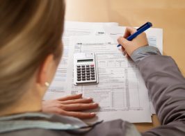 Woman Hand Filling Income Tax Forms With Calculator